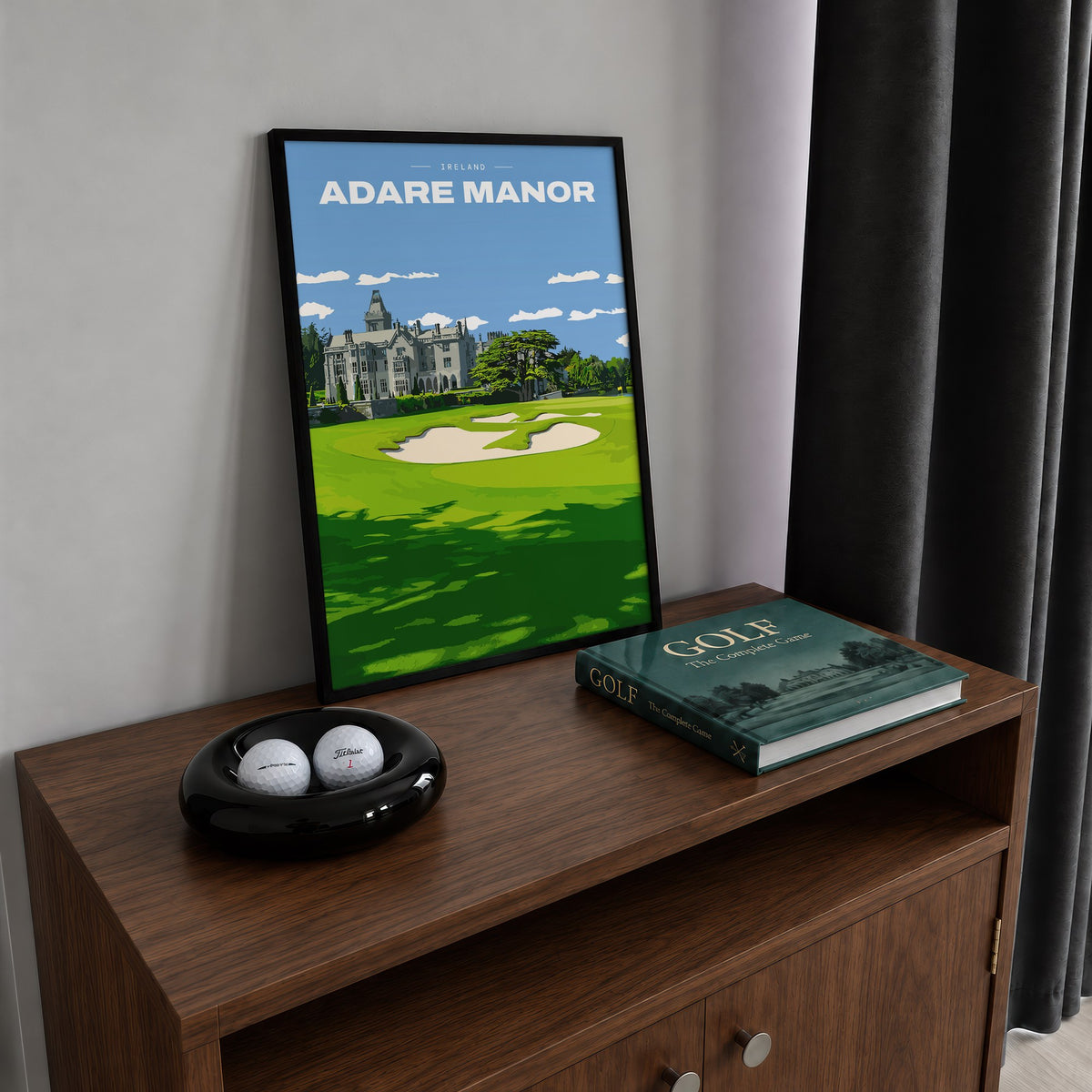 Adare Manor golf print of the manor house behind a green and bunkers, framed on a walnut cabinet beside golf balls and a golf book