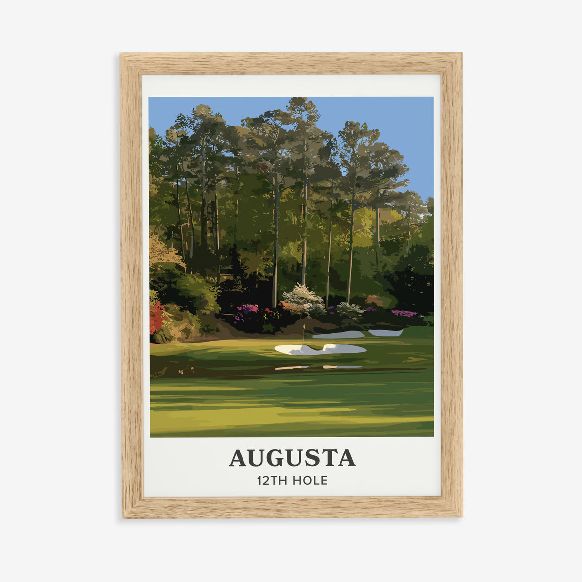 Augusta 12th hole golf print of a par 3 green below azaleas, cream border, in a natural wood frame on a plain wall