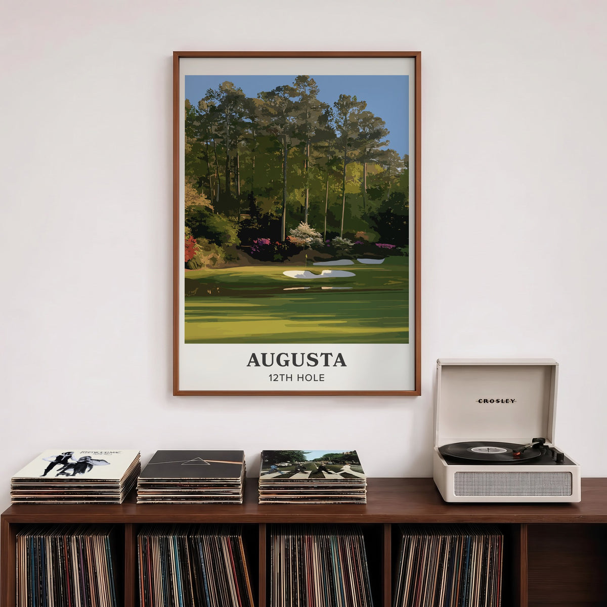 Augusta 12th hole golf print of a par 3 green below azaleas, cream border, framed above a record shelf beside a turntable