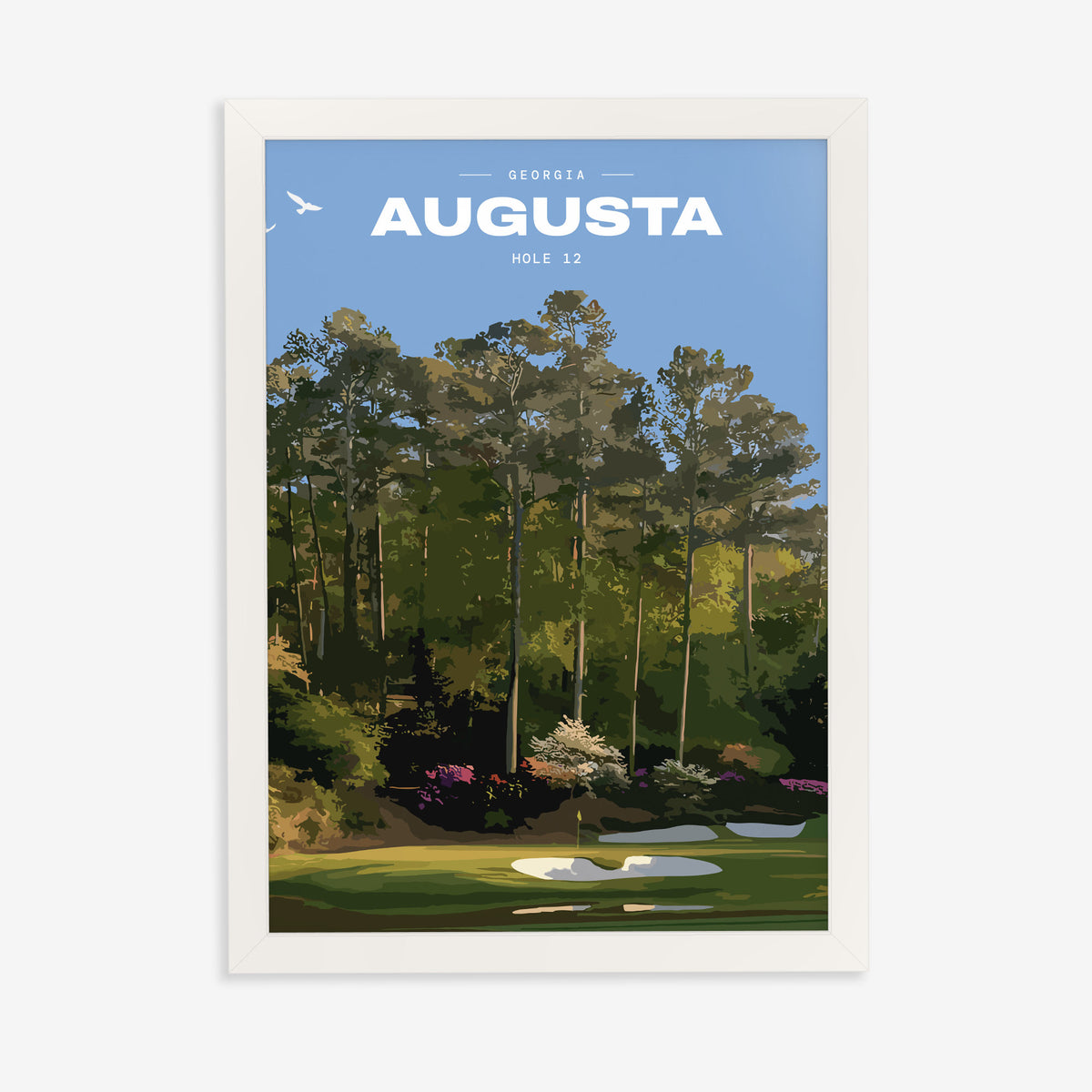 Augusta 12th hole golf print of a par 3 green below azaleas and pines, in a white frame on a plain wall