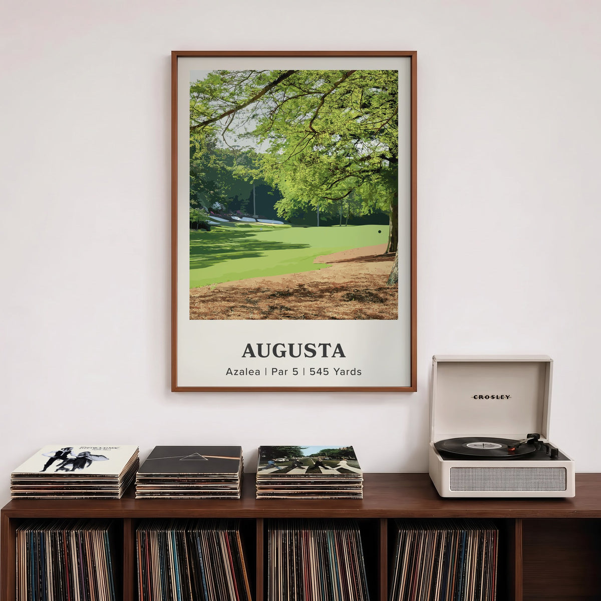 Augusta 13th hole golf print of a par 5 fairway under oak and pines, framed above a record shelf beside a turntable