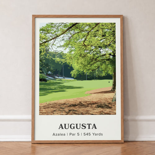 Augusta 13th hole golf print of a par 5 fairway under oak and pines, in an oak frame, leaning against a wall on a herringbone floor