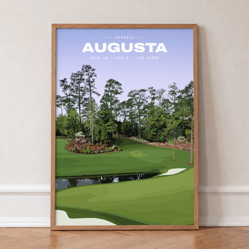 Augusta 16th hole golf print of a par 3 green across water, azaleas behind, in an oak frame, leaning against a wall on a herringbone floor