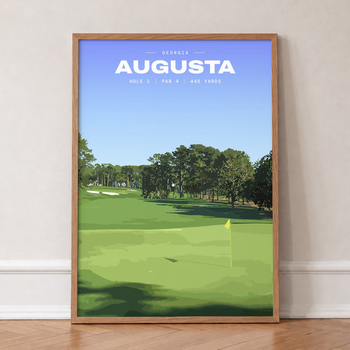 Augusta 1st hole golf print of an uphill fairway to a yellow flag, in an oak frame, leaning against a wall on a herringbone floor
