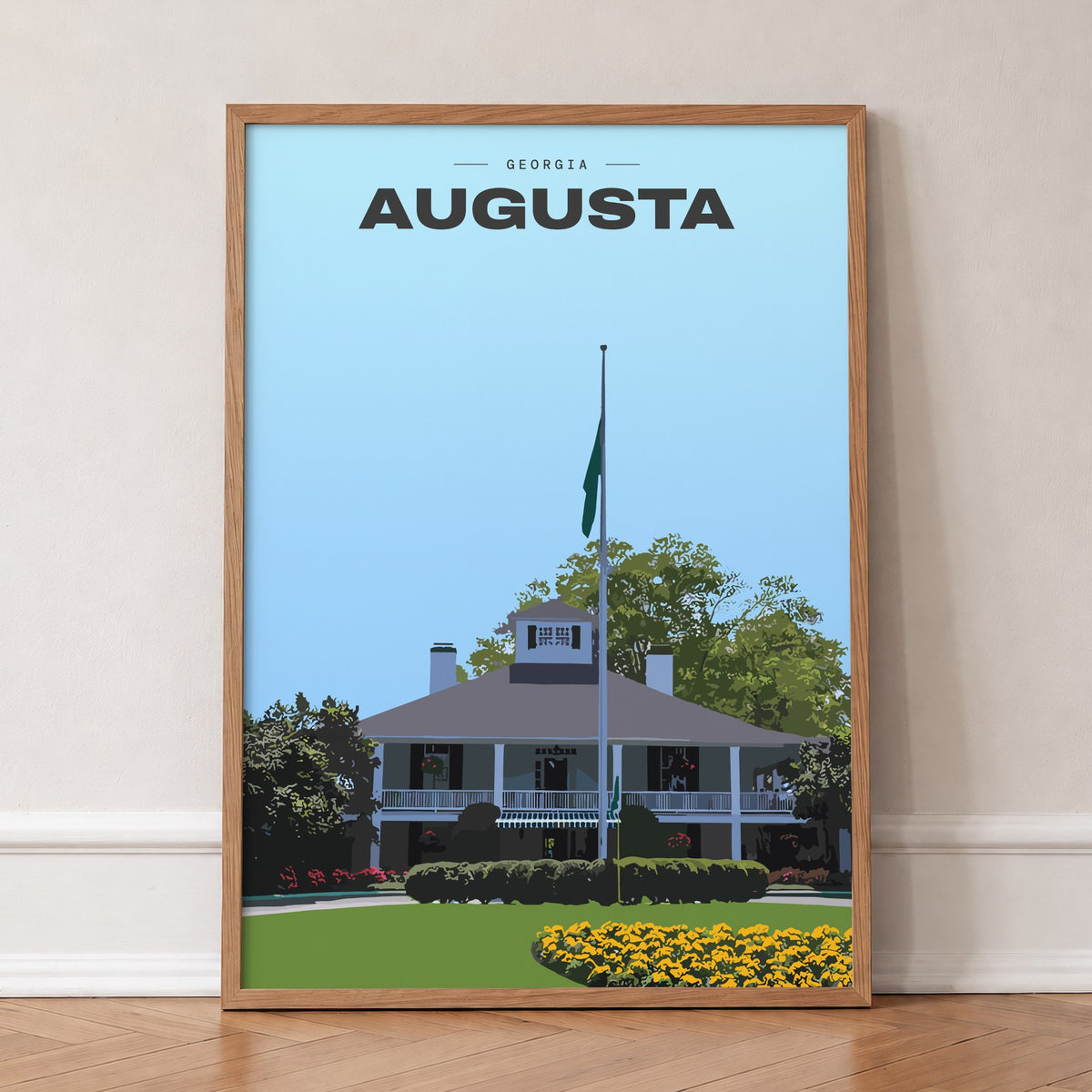 Augusta The Clubhouse golf print of the white clubhouse and yellow flowers, in an oak frame, leaning against a wall on a herringbone floor