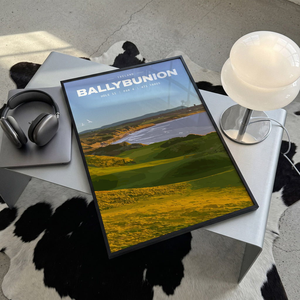 Ballybunion 11th hole golf print of dunes running down to an Atlantic bay, framed, lying on a steel table on a cowhide rug
