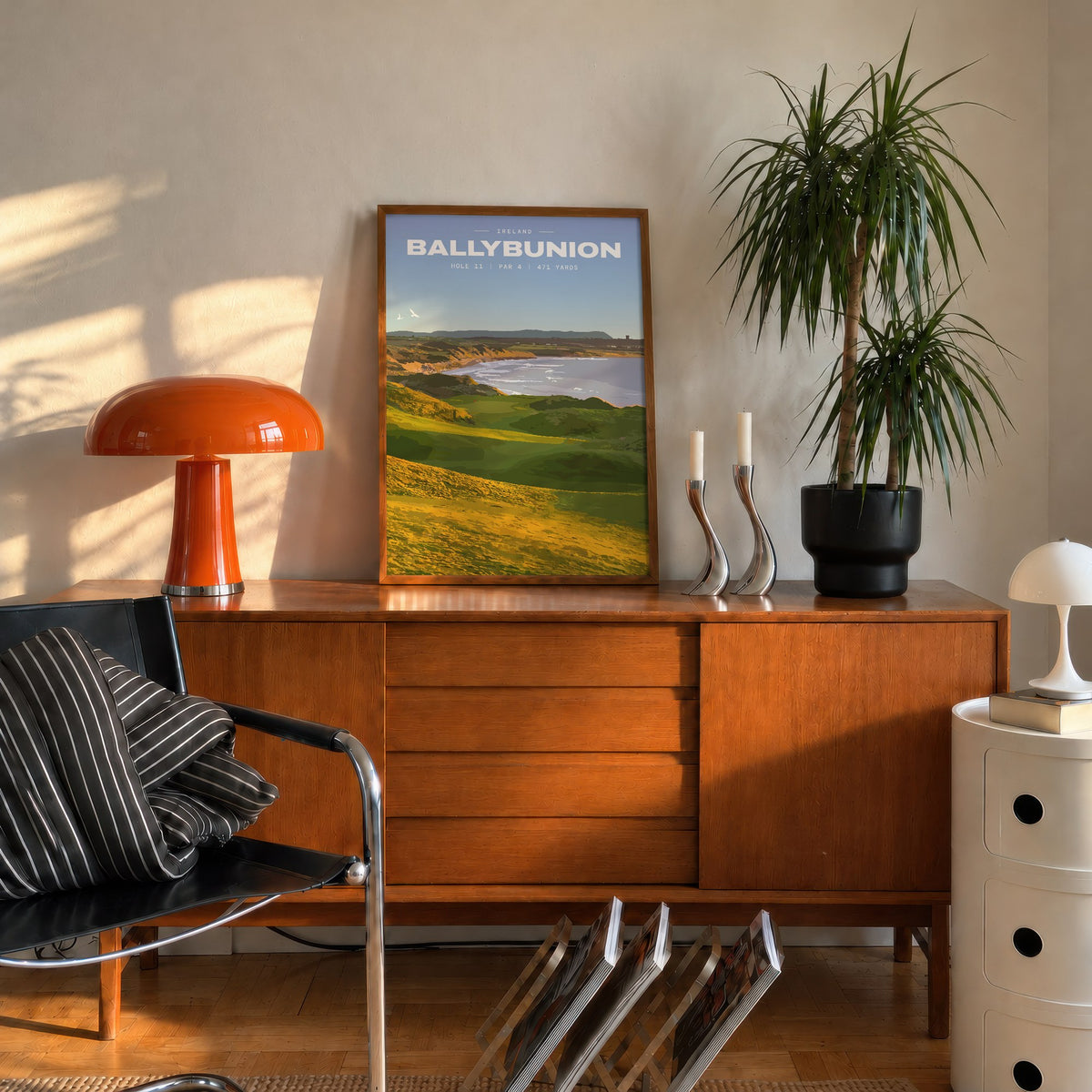 Ballybunion 11th hole golf print of dunes running down to an Atlantic bay, framed on a mid-century sideboard beside an orange lamp