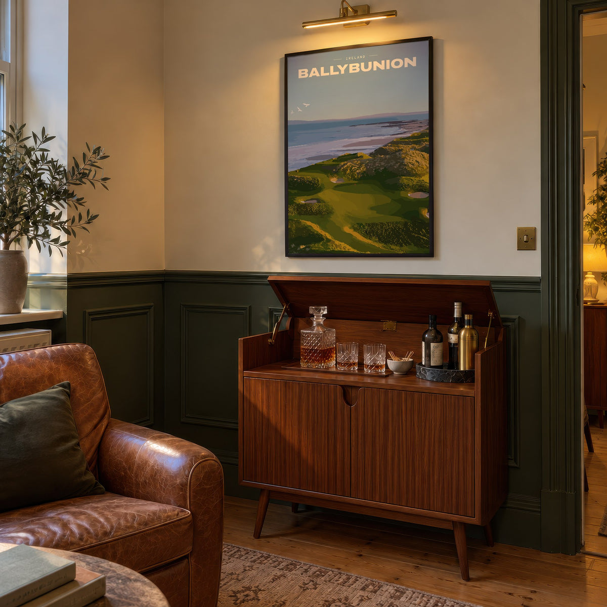 Ballybunion golf print of links greens in the dunes above the sea, framed above a bar cabinet beside a leather armchair