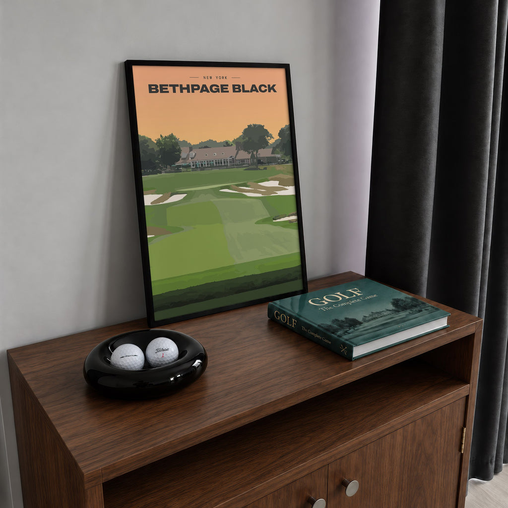 Bethpage Black golf print of a bunkered fairway up to the clubhouse, framed on a walnut cabinet beside golf balls and a golf book