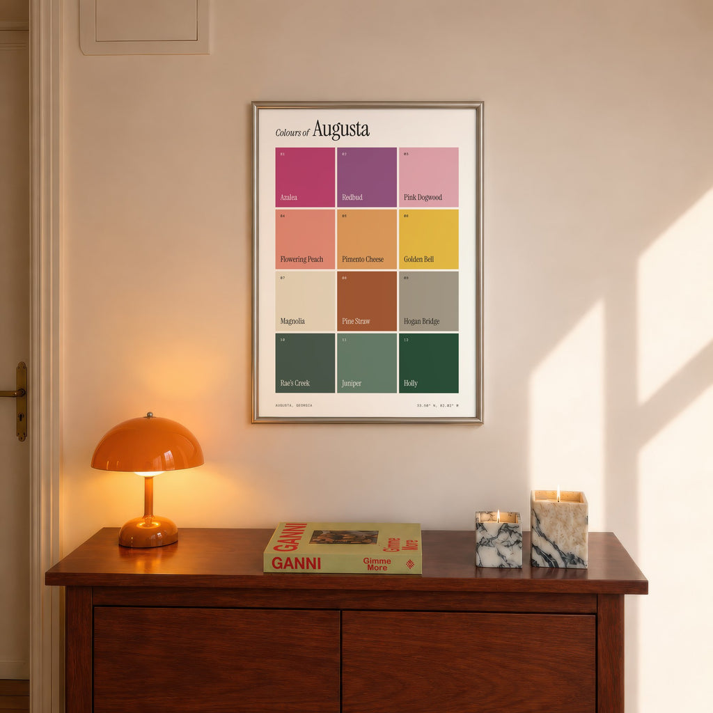 Colours of Augusta print of twelve named colour squares on white, framed above a console beside an orange lamp