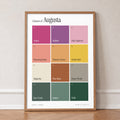 Colours of Augusta print of twelve named colour squares on white, in an oak frame, leaning against a wall on a herringbone floor
