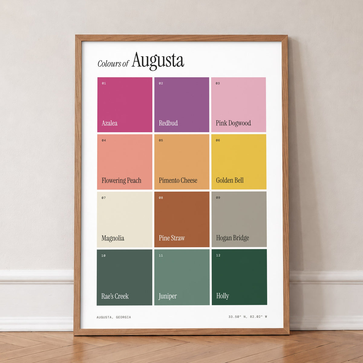 Colours of Augusta print of twelve named colour squares on white, in an oak frame, leaning against a wall on a herringbone floor