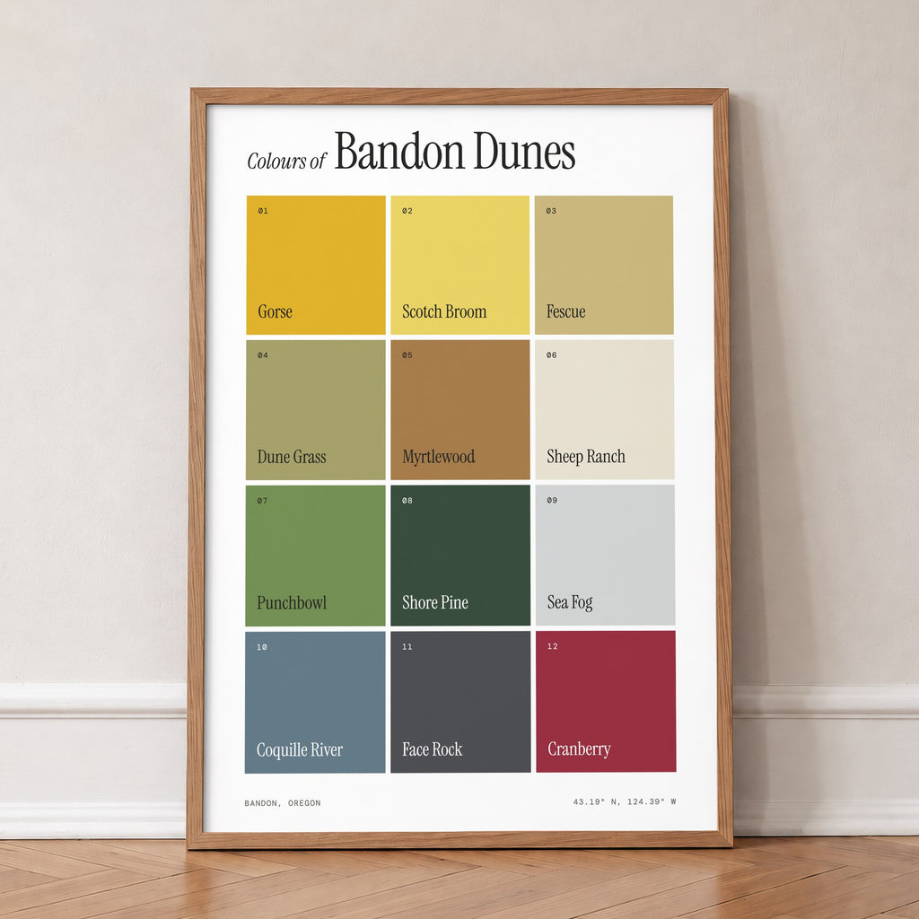Colours of Bandon Dunes print of twelve named colour squares on white, in an oak frame, leaning against a wall on a herringbone floor