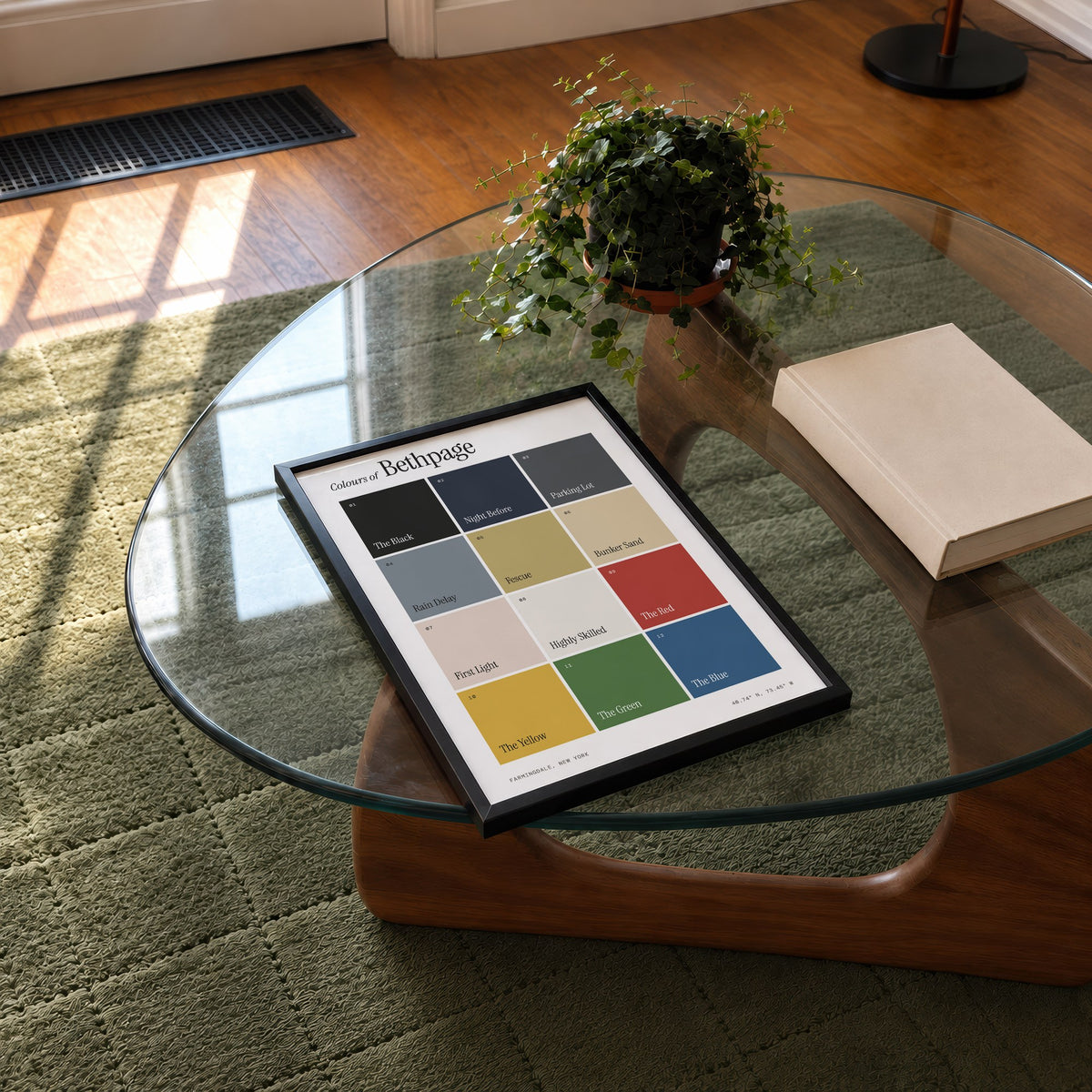 Colours of Bethpage print of twelve named colour squares on white, framed on a glass coffee table
