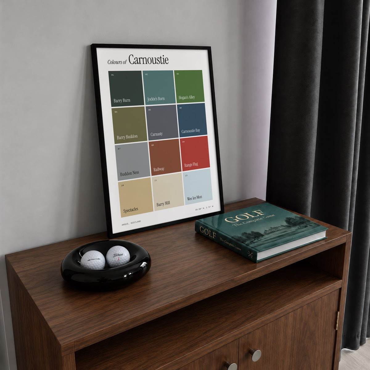 Colours of Carnoustie print of twelve named colour squares on white, framed on a walnut cabinet beside golf balls and a golf book
