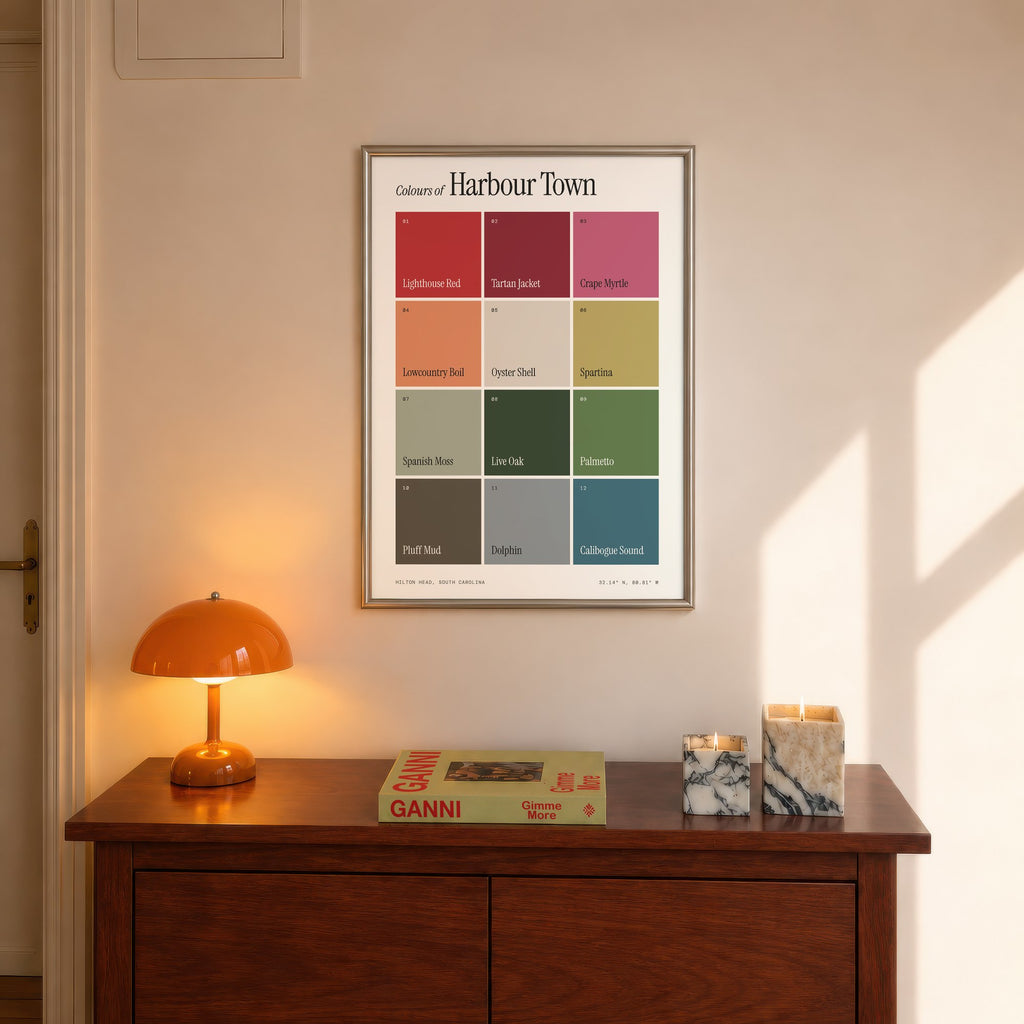Colours of Harbour Town print of twelve named colour squares on white, framed above a console beside an orange lamp