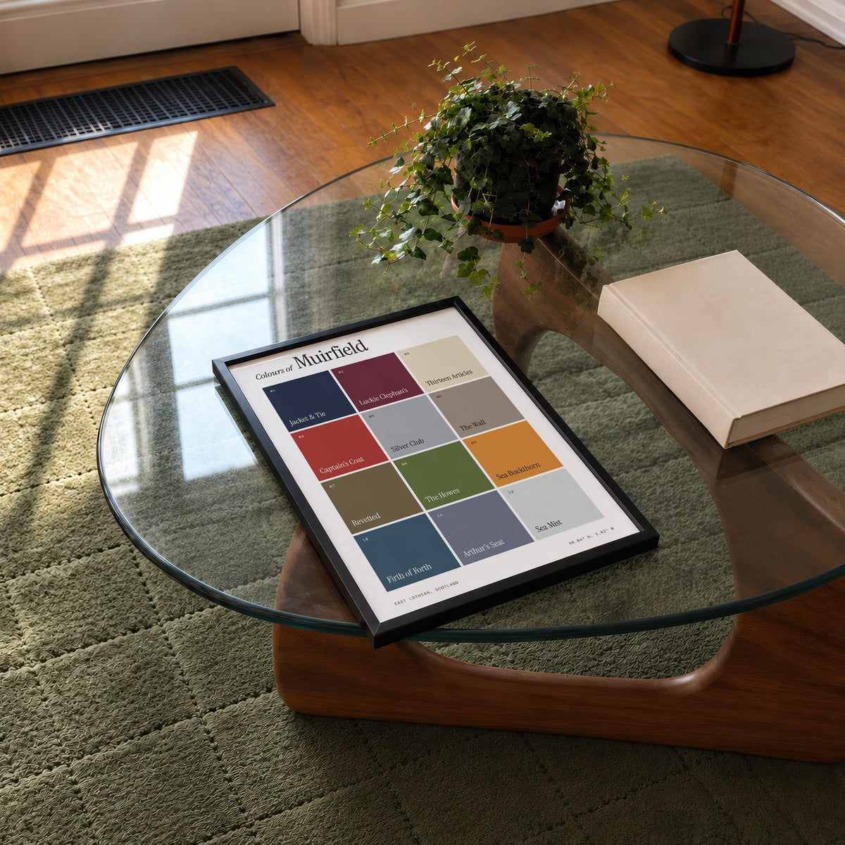 Colours of Muirfield print of twelve named colour squares on white, framed on a glass coffee table