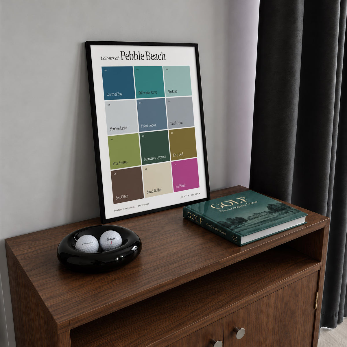 Colours of Pebble Beach print of twelve named colour squares on white, framed on a walnut cabinet beside golf balls and a golf book