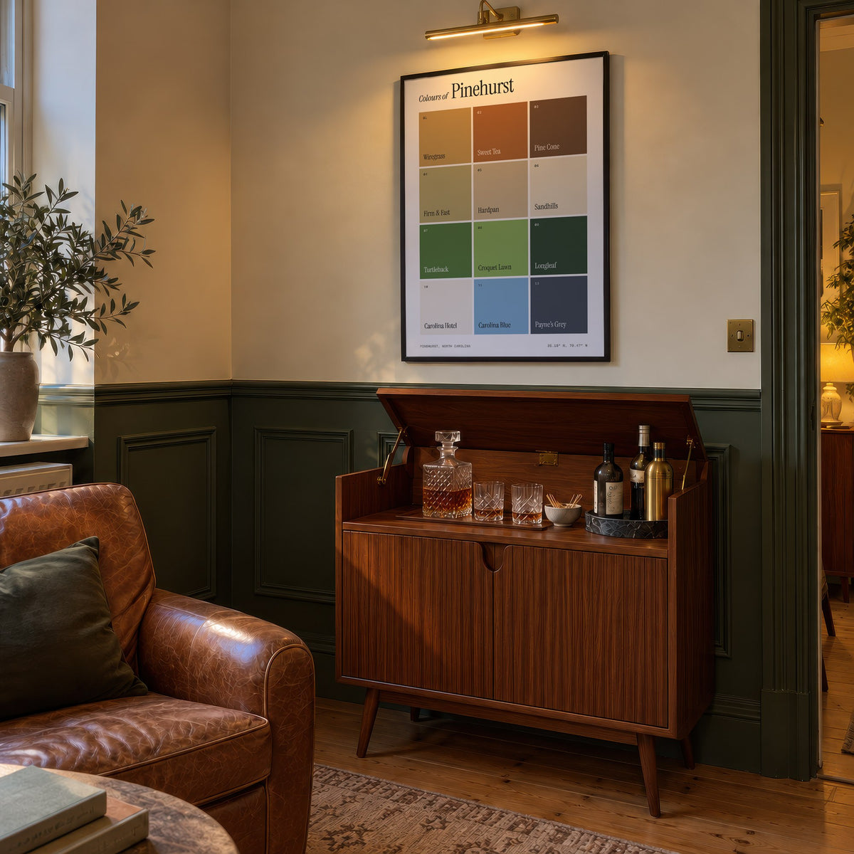 Colours of Pinehurst print of twelve named colour squares on white, framed above a bar cabinet beside a leather armchair