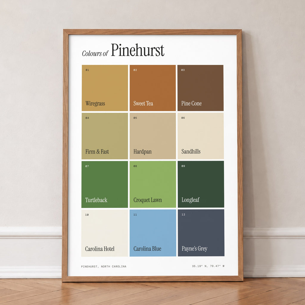 Colours of Pinehurst print of twelve named colour squares on white, in an oak frame, leaning against a wall on a herringbone floor
