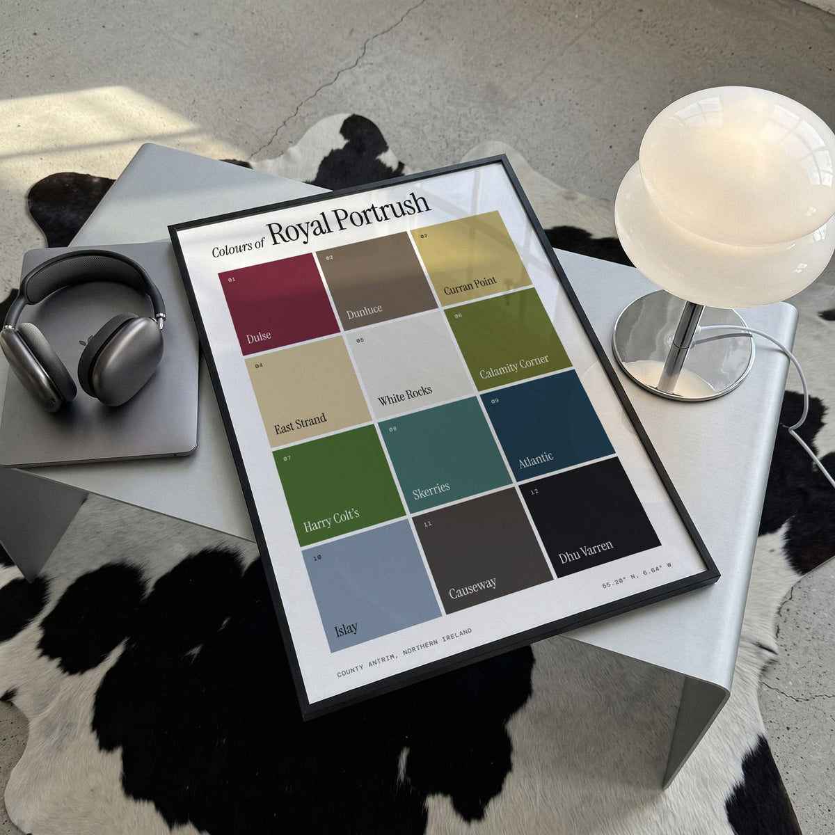 Colours of Royal Portrush print of twelve named colour squares on white, framed, lying on a steel table on a cowhide rug