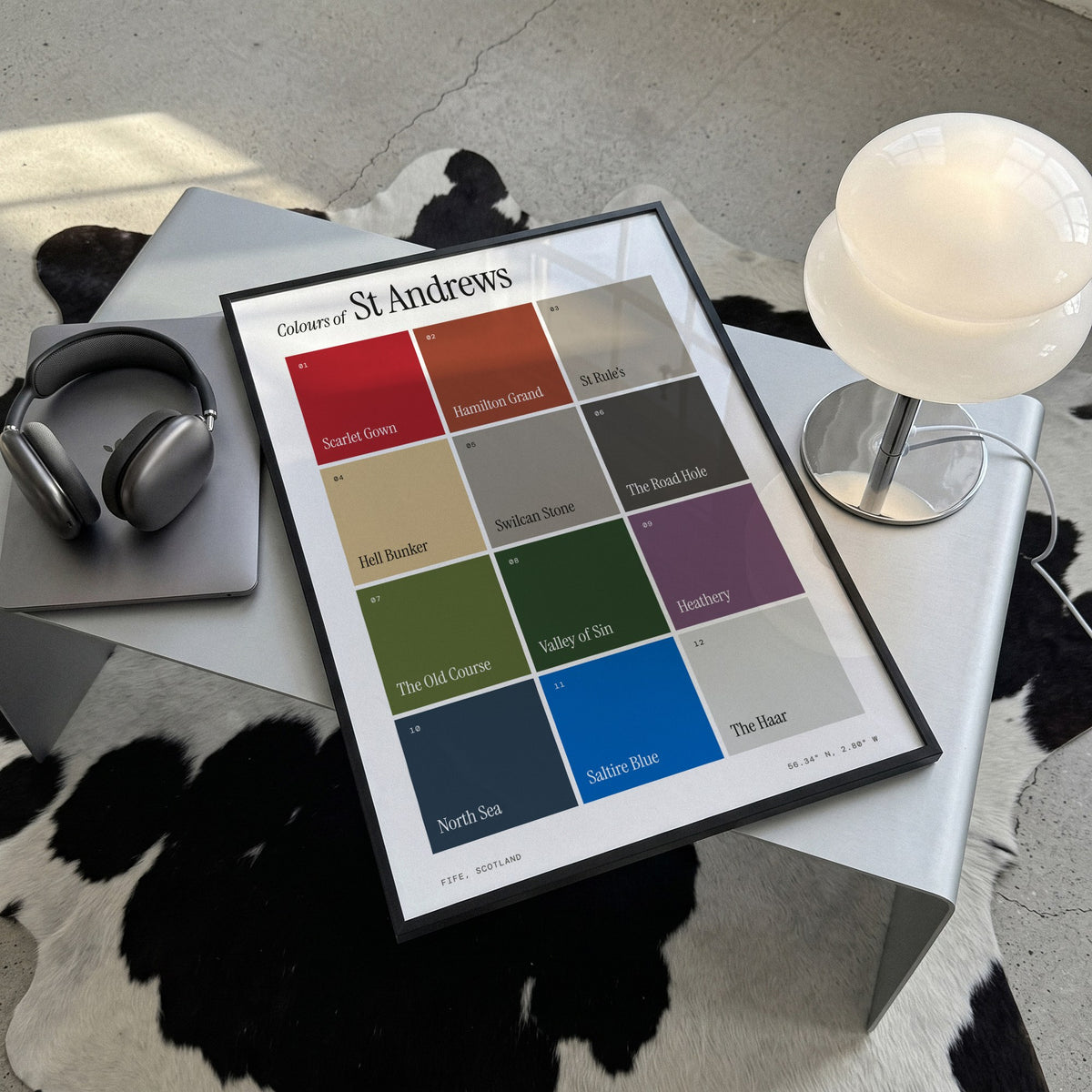 Colours of St Andrews print of twelve named colour squares on white, framed, lying on a steel table on a cowhide rug