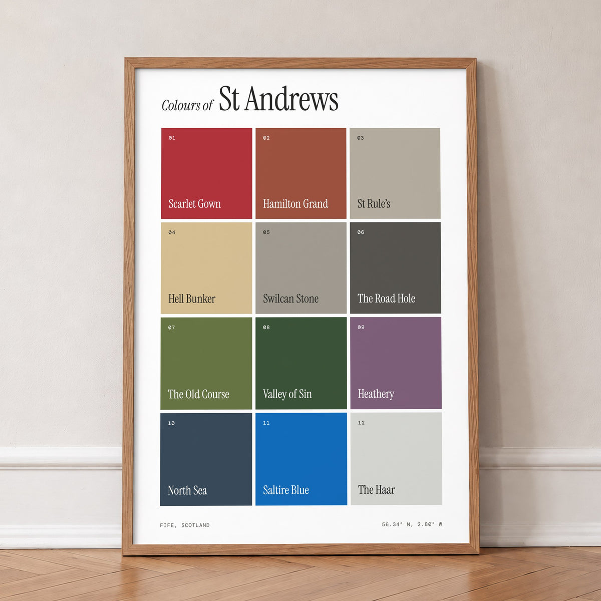 Colours of St Andrews print of twelve named colour squares on white, in an oak frame, leaning against a wall on a herringbone floor