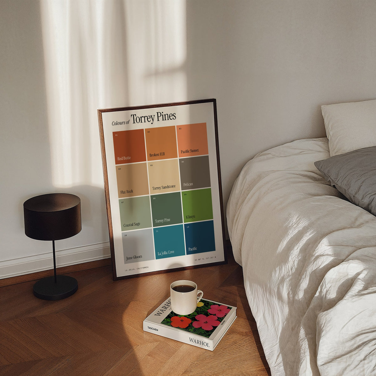 Colours of Torrey Pines print of twelve named colour squares on white, framed, leaning by a bed