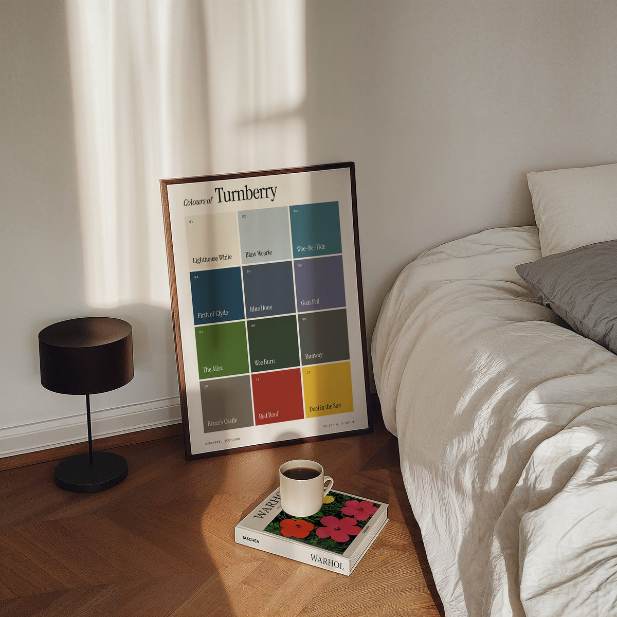 Colours of Turnberry print of twelve named colour squares on white, framed, leaning by a bed