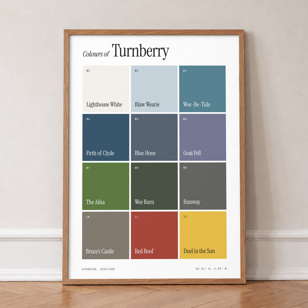 Colours of Turnberry print of twelve named colour squares on white, in an oak frame, leaning against a wall on a herringbone floor