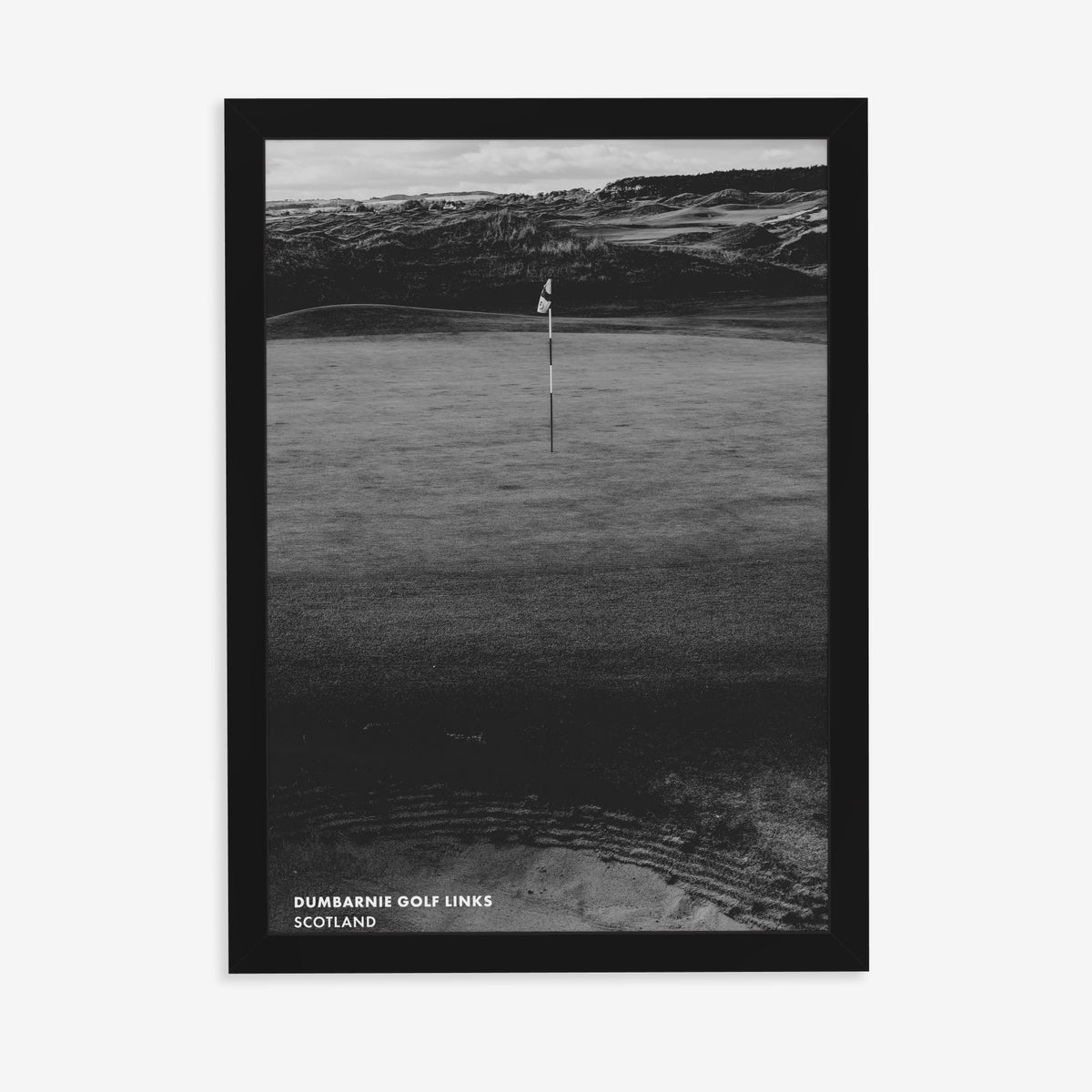 Dumbarnie golf print of a black and white photo of a flag below dunes, in a black frame on a plain wall