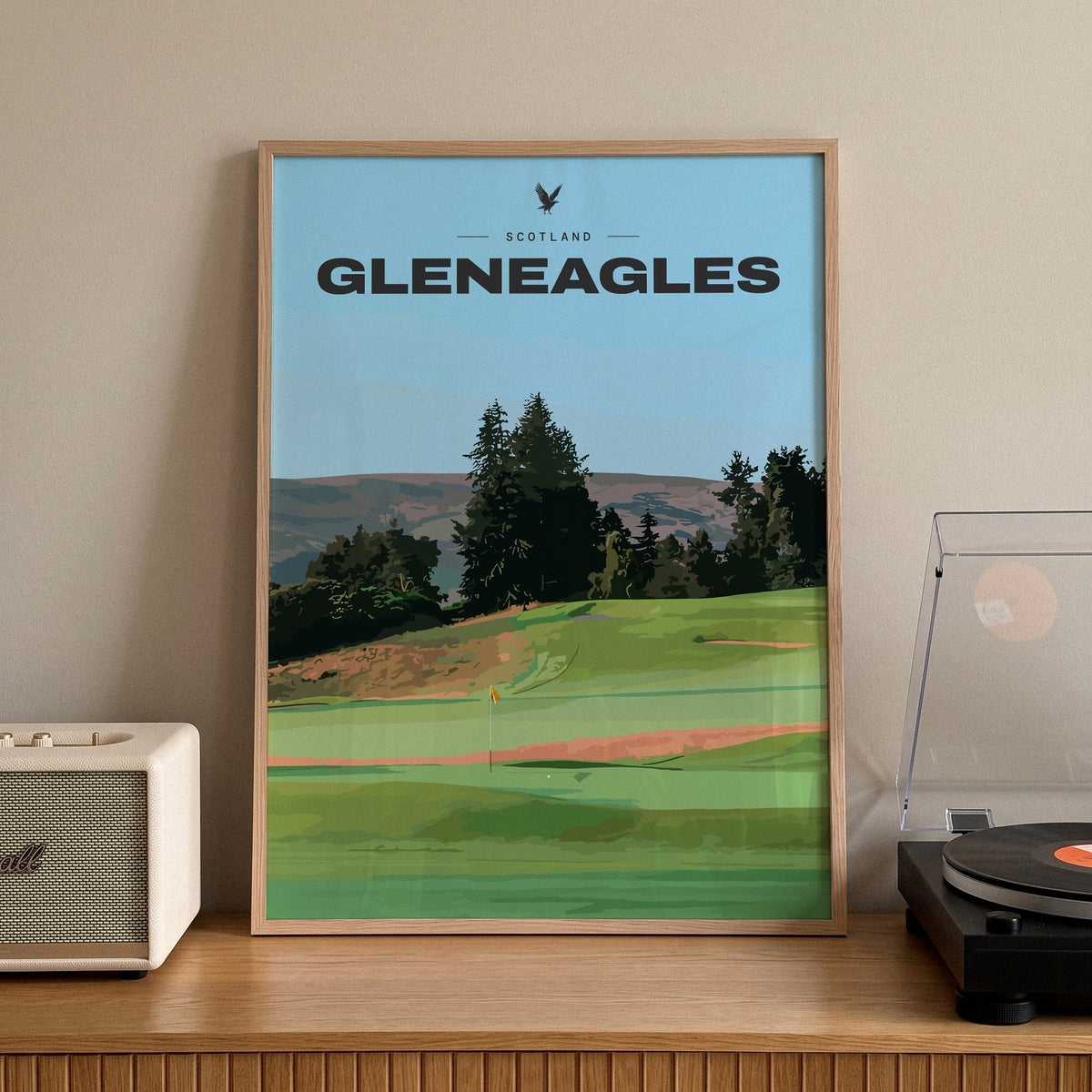 Gleneagles golf print of a green below pines and Perthshire hills, framed on a sideboard beside a record player