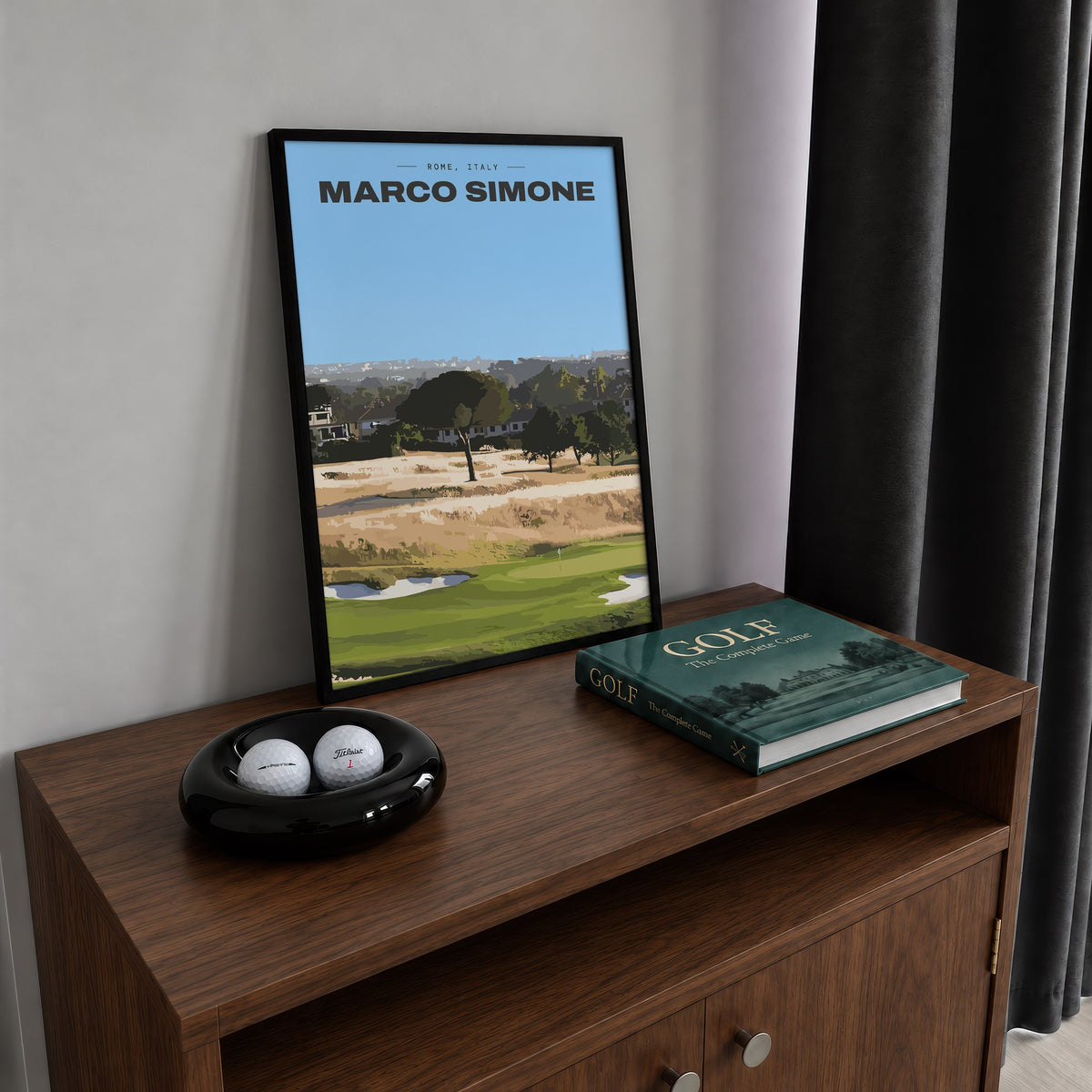Marco Simone golf print of a green below umbrella pines and gold rough, framed on a walnut cabinet beside golf balls and a golf book