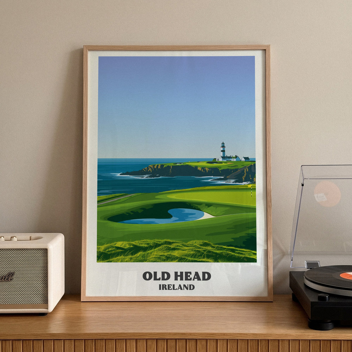 Old Head golf print of a lighthouse on a headland above a green, framed on a sideboard beside a record player