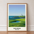 Old Head golf print of a lighthouse on a headland above a green, in an oak frame, leaning against a wall on a herringbone floor