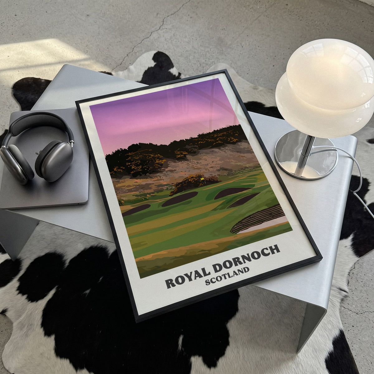 Royal Dornoch golf print of a plateau green below a gorse hill at dusk, framed, lying on a steel table on a cowhide rug