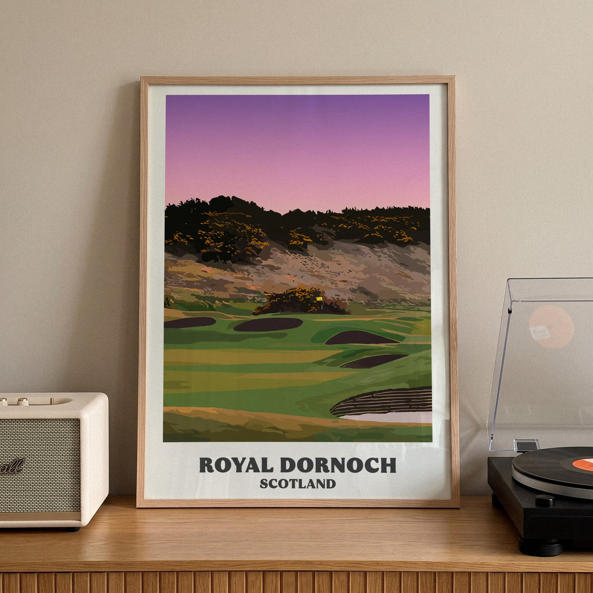 Royal Dornoch golf print of a plateau green below a gorse hill at dusk, framed on a sideboard beside a record player