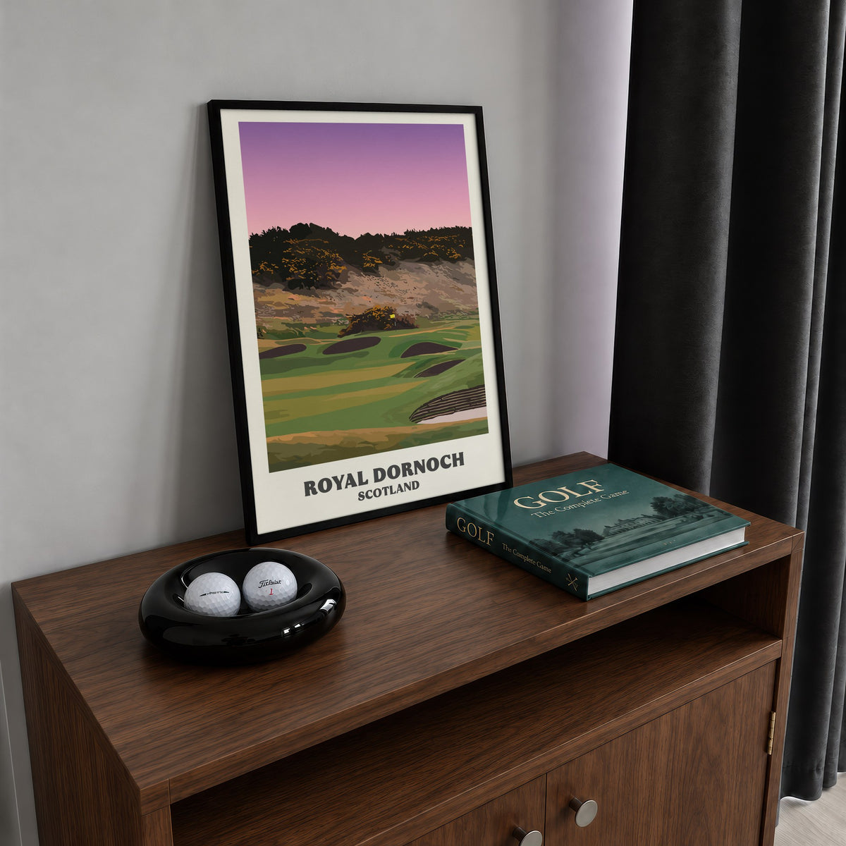 Royal Dornoch golf print of a plateau green below a gorse hill at dusk, framed on a walnut cabinet beside golf balls and a golf book