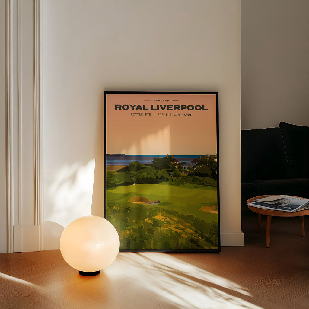 Royal Liverpool Little Eye golf print of a raised par 3 green at sunset, framed, leaning against a wall beside a globe lamp