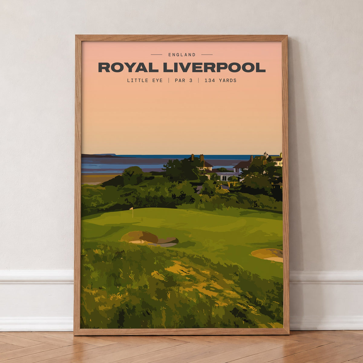 Royal Liverpool Little Eye golf print of a raised par 3 green at sunset, in an oak frame, leaning against a wall on a herringbone floor