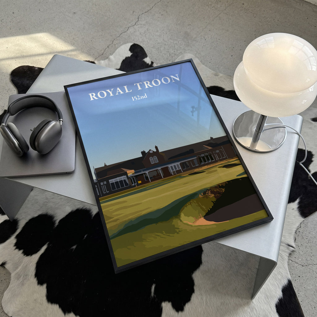 Royal Troon 2024 golf print of the clubhouse behind the 18th green, framed, lying on a steel table on a cowhide rug