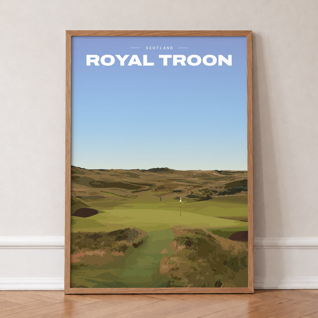 Royal Troon golf print of a links fairway through dunes to a flag, in an oak frame, leaning against a wall on a herringbone floor