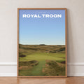 Royal Troon golf print of a links fairway through dunes to a flag, in an oak frame, leaning against a wall on a herringbone floor