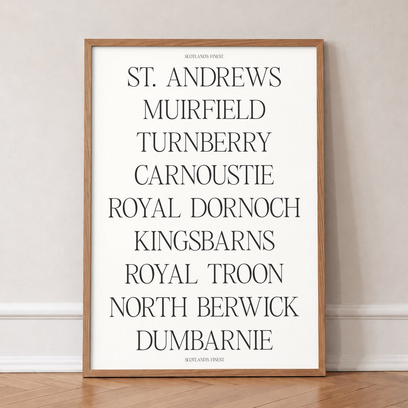 Scotland's Finest golf print of nine Scottish course names in serif type, in an oak frame, leaning against a wall on a herringbone floor