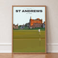 St Andrews Old Course golf print of the 18th green and flag below the town, in an oak frame, leaning against a wall on a herringbone floor
