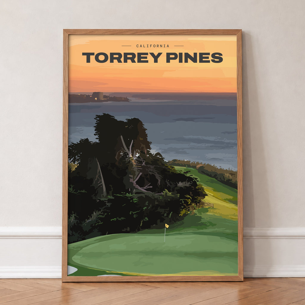 Torrey Pines golf print of a clifftop green above the Pacific at sunset, in an oak frame, leaning against a wall on a herringbone floor