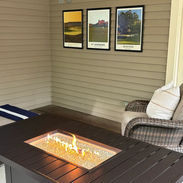 Three framed golf course prints on a porch wall above a fire table